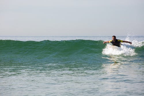 确定的男性冲浪者骑冲浪板在海浪的肚子上 · 免费素材图片