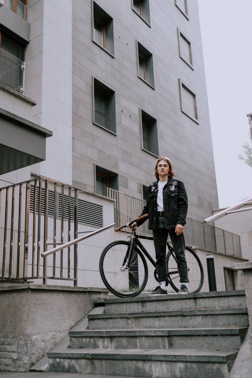 黑夹克和黑裤子站在自行车上的人 · 免费素材图片