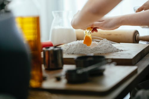 拿着黄色的塑料瓶，倒黄色液体在黑色陶瓷碗上的人 · 免费素材图片