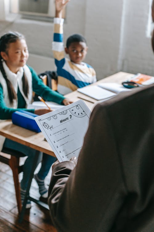 黑人小学生在上课时在教室里举起手 · 免费素材图片