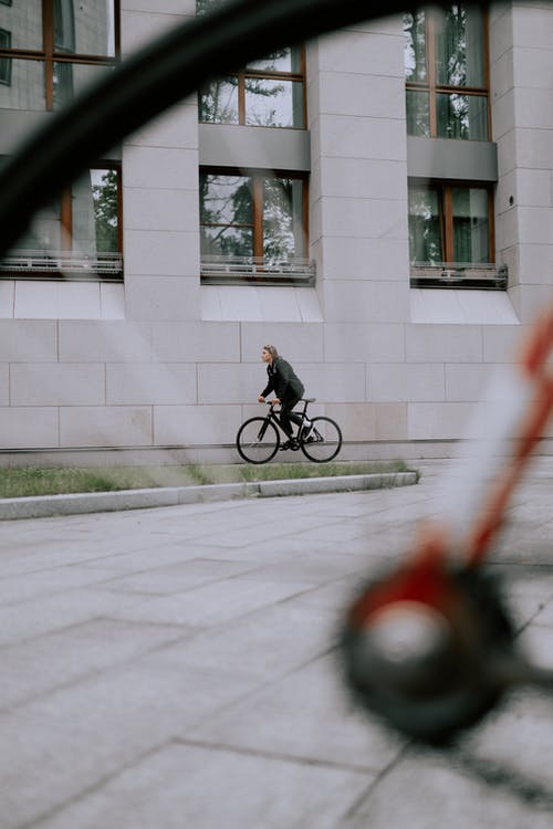 黑色外套骑自行车在灰色的混凝土路上的男人 · 免费素材图片