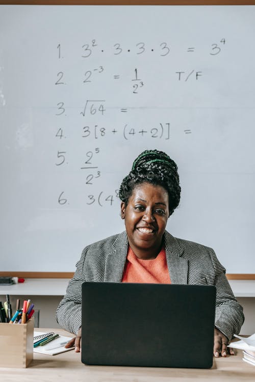 积极黑人老师使用笔记本电脑和微笑 · 免费素材图片