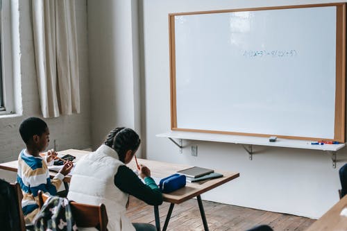 勤奋的黑人学生，坐在现代教室的桌子旁 · 免费素材图片