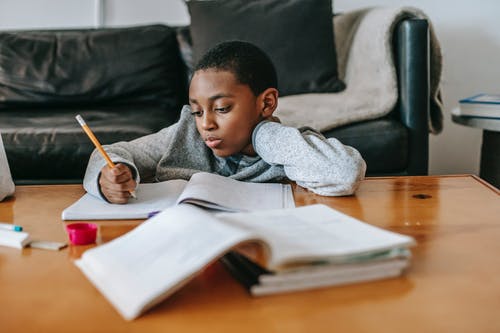 沉思的黑人男孩做作业 · 免费素材图片