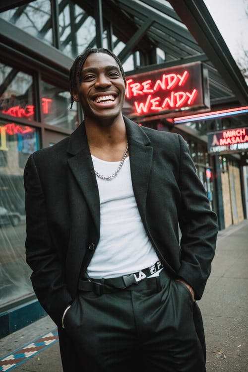 自信的年轻黑人男子，站在大街上和微笑 · 免费素材图片