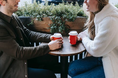 拿着红色陶瓷杯子的灰色毛线衣的妇女坐在棕色木椅子 · 免费素材图片