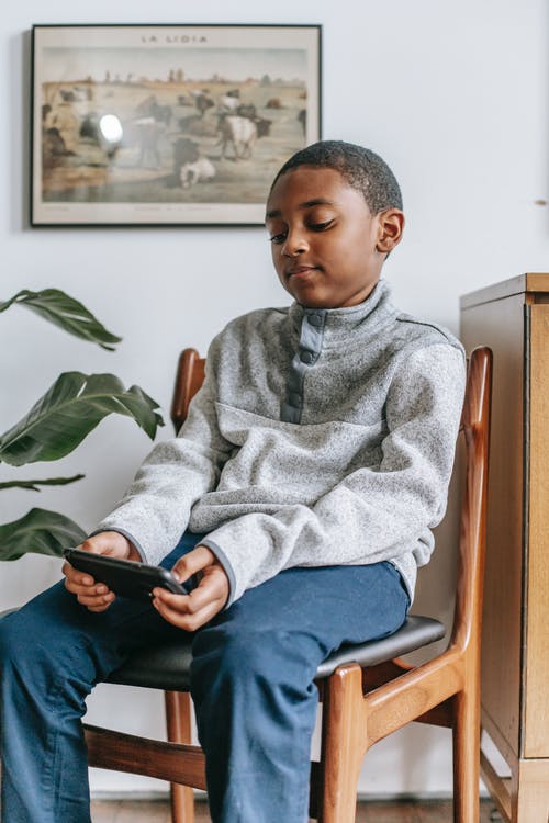 集中与智能手机的黑人男孩 · 免费素材图片