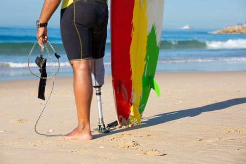 裁剪不露面截肢男性冲浪者与冲浪板站在海边 · 免费素材图片