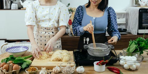 拿着棕色木筷子的白色和蓝色圆点连衣裙的女人 · 免费素材图片