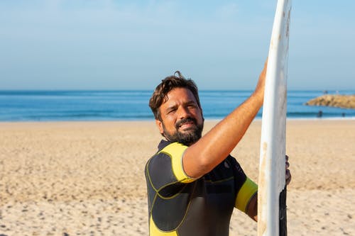 积极男性冲浪者站在一起在沙滩上的冲浪板 · 免费素材图片