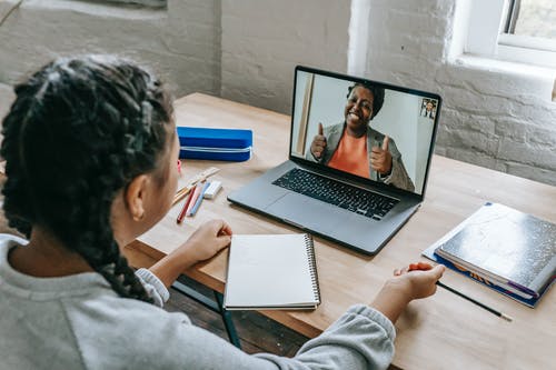 种族的女孩在笔记本电脑上与老师在线视频聊天 · 免费素材图片