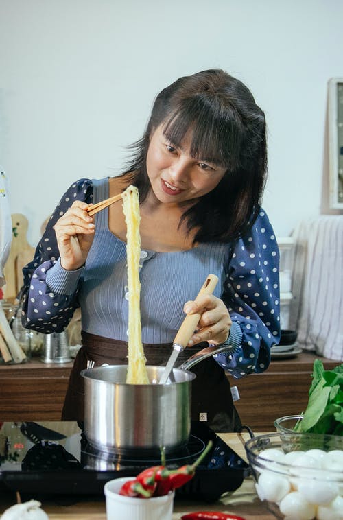 拿着筷子的蓝色和白色的圆点长袖衬衫的女孩 · 免费素材图片