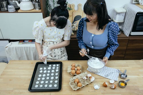 拿着饼干的棕色木托盘的白色和蓝色长袖衬衫的女人 · 免费素材图片