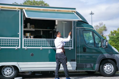 服务员打开停在绿色公园的食物卡车 · 免费素材图片