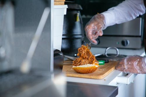 厨师把炸猪肉放在汉堡的面包上 · 免费素材图片