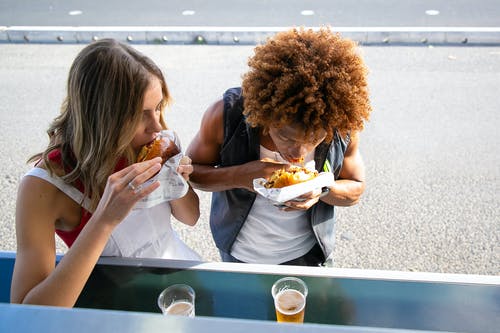 多种族的夫妇一起在午餐时间咬汉堡包 · 免费素材图片