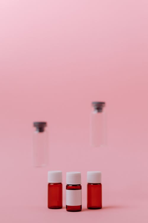 粉红色的表面上的三个小玻璃瓶 · 免费素材图片