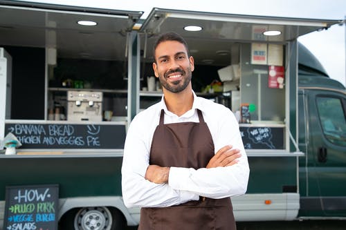 站立与横渡的胳膊的快乐的种族男性食物卡车侍者 · 免费素材图片