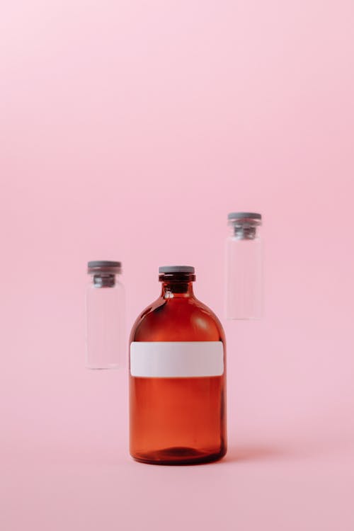 粉红色的表面上的三个小玻璃瓶 · 免费素材图片