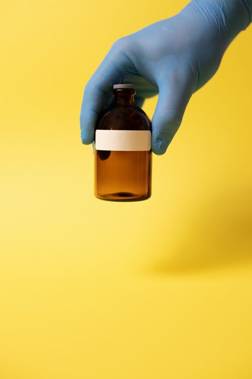 拿着棕色玻璃瓶的人 · 免费素材图片