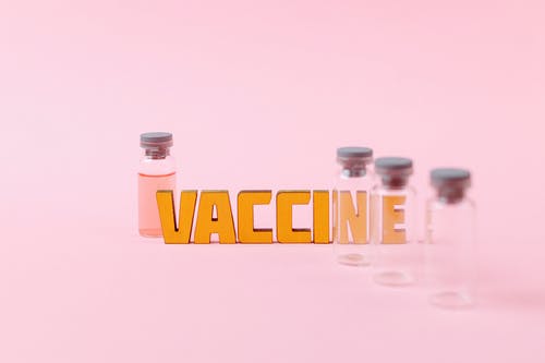 空的透明玻璃瓶旁边的疫苗文字 · 免费素材图片