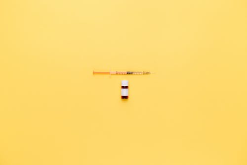 小瓶和黄色表面上的注射器 · 免费素材图片