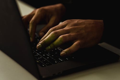 裁剪无法识别的人在笔记本电脑键盘上打字 · 免费素材图片