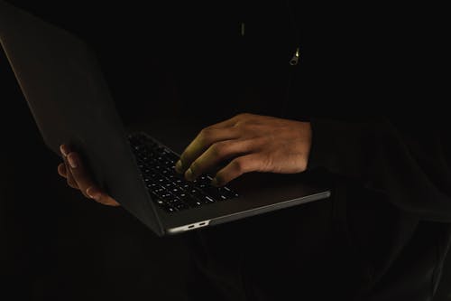 作物在黑暗中使用笔记本电脑的面目全非的人 · 免费素材图片