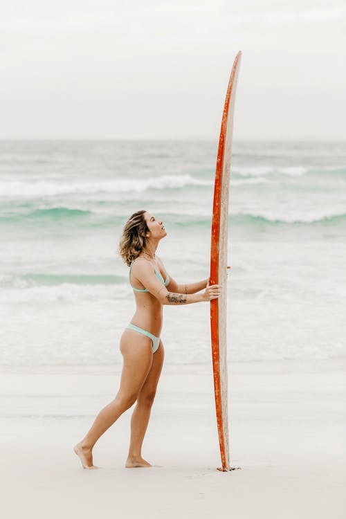 冲浪板在沙滩上的女性旅行者 · 免费素材图片