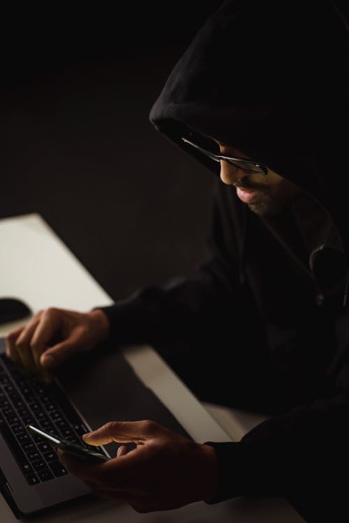 作物黑客在黑暗中浏览笔记本电脑和智能手机 · 免费素材图片