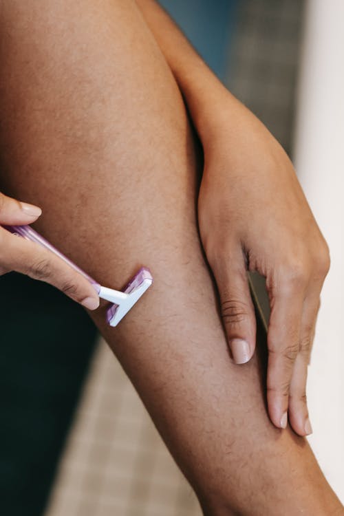 作物族裔女人用一次性剃须刀刮腿 · 免费素材图片