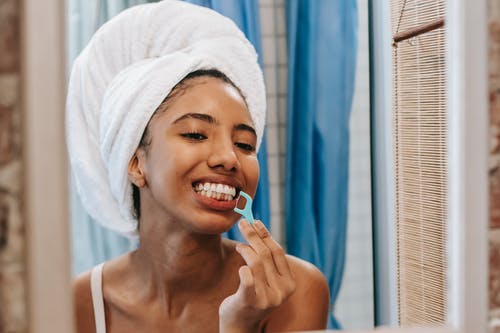 族裔女人用牙线清洁牙齿 · 免费素材图片