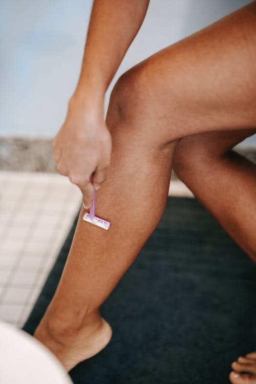 种族的女人用剃刀在浴室剃须腿 · 免费素材图片