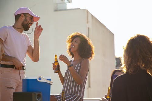 性格开朗的多民族朋友喝啤酒，在屋顶上聊天 · 免费素材图片