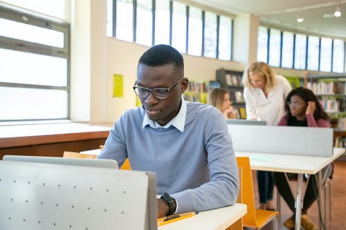 聪明的年轻种族人在大学期间的课上浏览笔记本电脑 · 免费素材图片