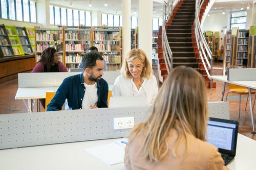 青年学生准备在图书馆中使用笔记本电脑的考试 · 免费素材图片