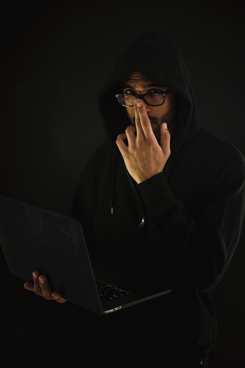 眼镜的男性计算机怪人与膝上型计算机在黑暗中 · 免费素材图片