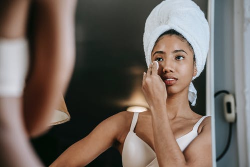裁剪族裔女人摸脸用化妆棉对镜子 · 免费素材图片