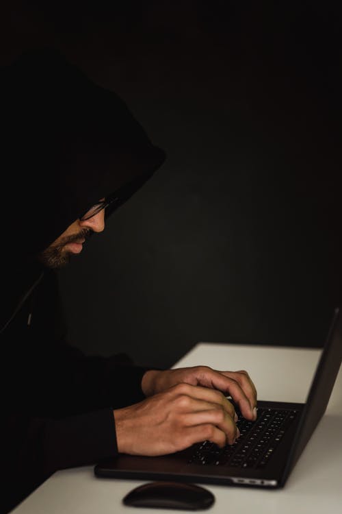 不可识别的民族黑客在桌上的笔记本电脑上打字 · 免费素材图片