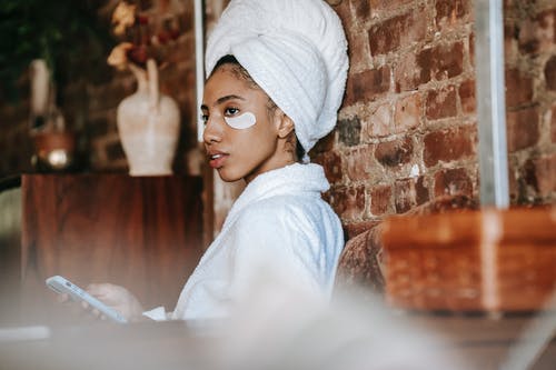 浴袍的年轻种族夫人在家洗完澡后使用智能手机 · 免费素材图片