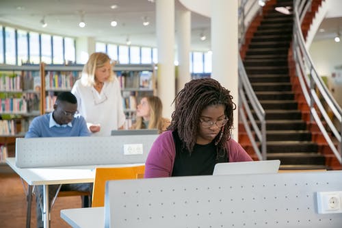 集中在图书馆上课时使用笔记本电脑的年轻多样化学生 · 免费素材图片