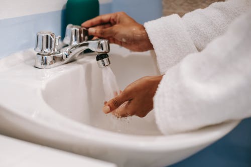 袍族裔女人穿着长袍在浴室里洗手 · 免费素材图片