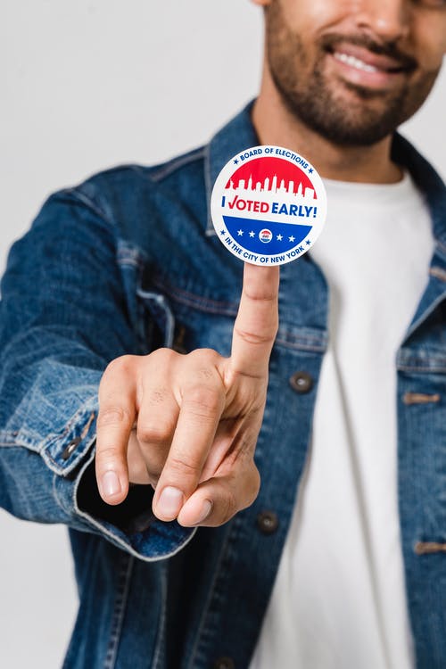 蓝色牛仔钮扣夹克显示投票贴纸的人 · 免费素材图片