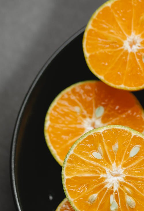 在黑色陶瓷碗中切多汁的新鲜橘子 · 免费素材图片