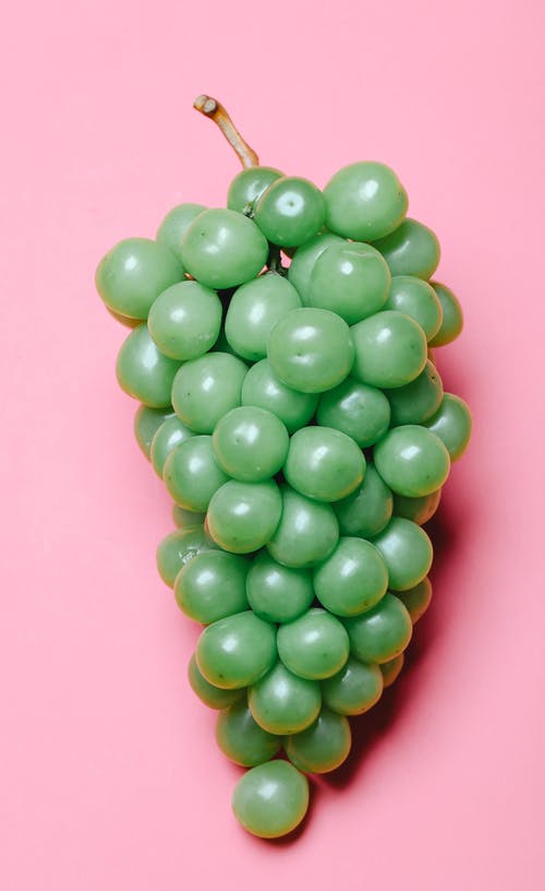粉红色的表面上的绿色圆形水果 · 免费素材图片
