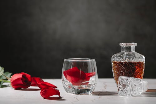 透明玻璃瓶与棕色木制的桌子上的红色液体 · 免费素材图片