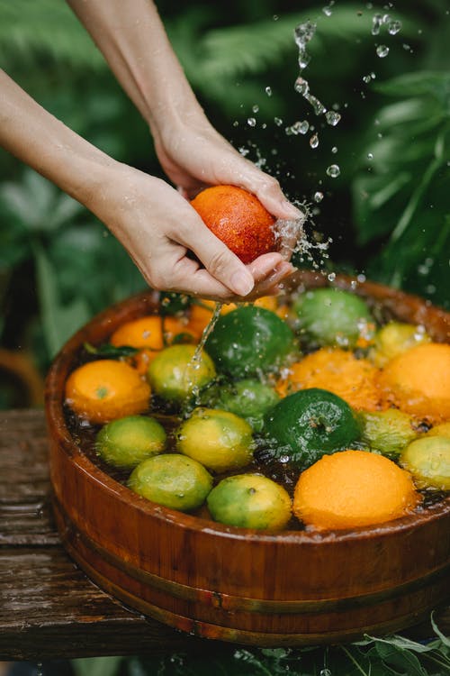 不可识别的女园丁洗柑橘在木质容器中的性质 · 免费素材图片