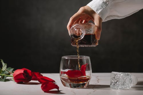 在透明的水杯上倒酒的人 · 免费素材图片