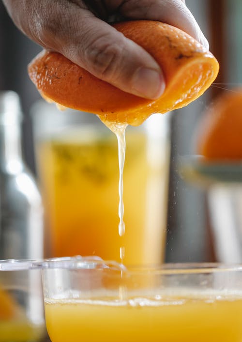 在透明的水杯上倒橙汁的人 · 免费素材图片