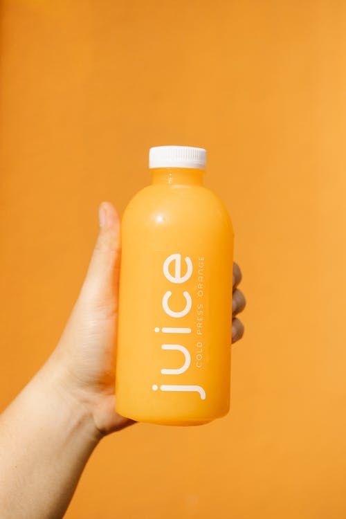 拿着黄色和白色塑料瓶的人 · 免费素材图片